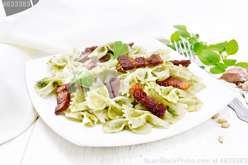 Image of Farfalle with pesto and bacon in plate on white board