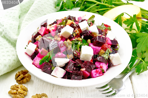 Image of Salad with beetroot and walnuts in plate on light board