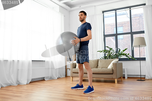 Image of man exercising with fitness ball at home