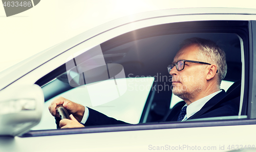 Image of happy senior businessman driving car