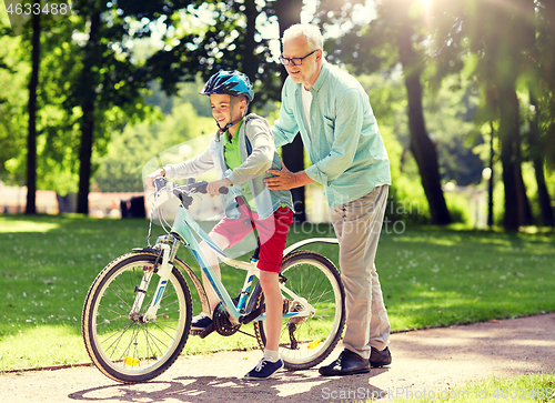 Image of grandfather and boy with bicycle at summer park