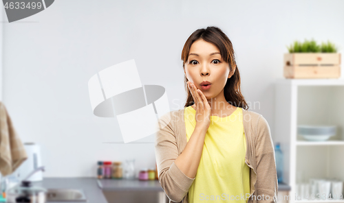 Image of surprised asian woman over kitchen background