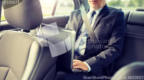 Image of senior businessman with laptop driving in car