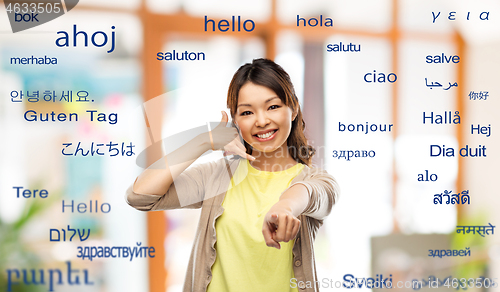 Image of woman making phone call gesture over foreign words