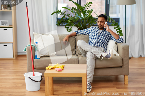 Image of man calling on smartphone after cleaning home