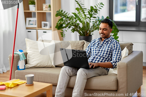 Image of man with laptop computer after home cleaning