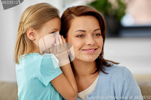 Image of daughter whispering secret to mother at home