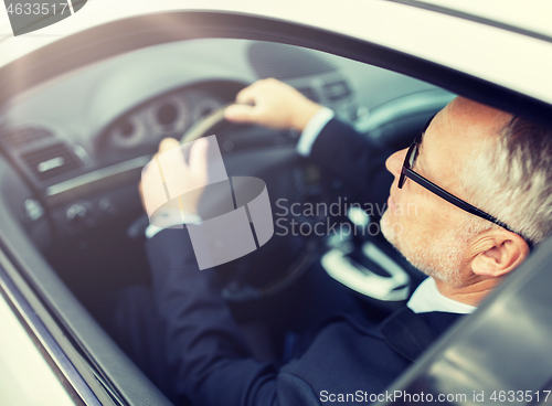 Image of happy senior businessman driving car