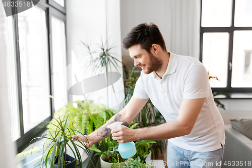 Image of man spraying houseplants with water at home