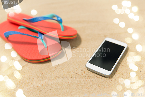 Image of smartphone and flip flops on beach sand