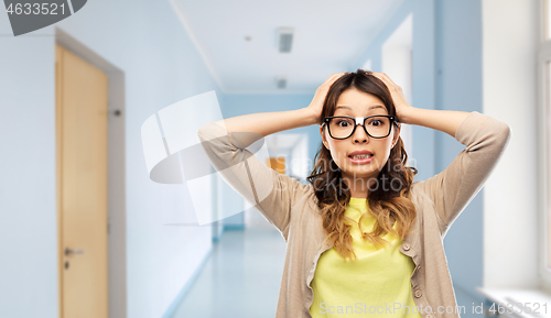 Image of stressed female student holding to head at school