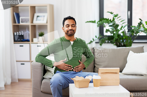 Image of pleased indian man eating takeaway food at home