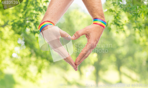 Image of male hands with gay pride wristbands showing heart