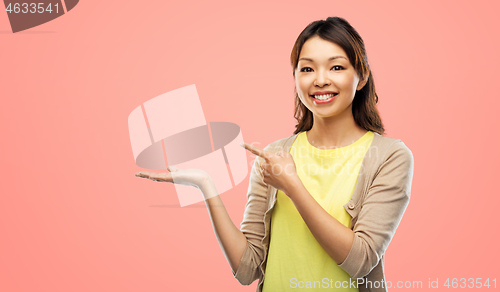 Image of happy asian woman holding something on hand