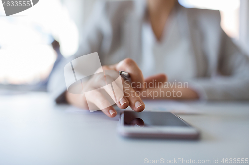 Image of hand of businesswoman using smartphone at office