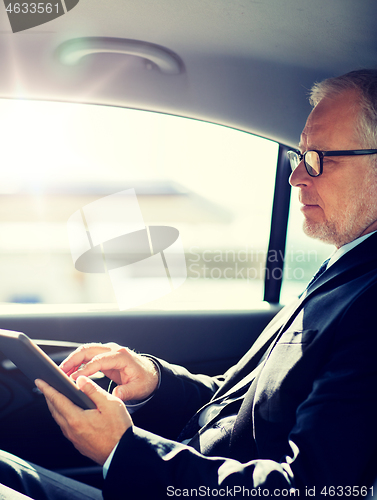 Image of senior businessman with tablet pc driving in car