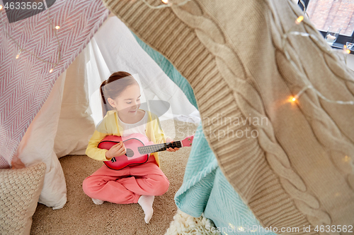 Image of little girl playing guitar in kids tent at home