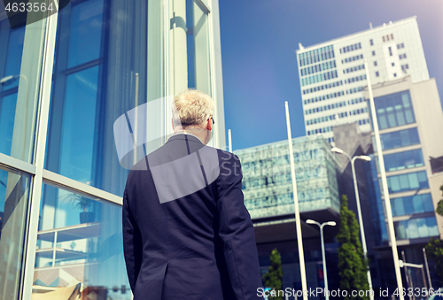 Image of senior businessman walking along city street