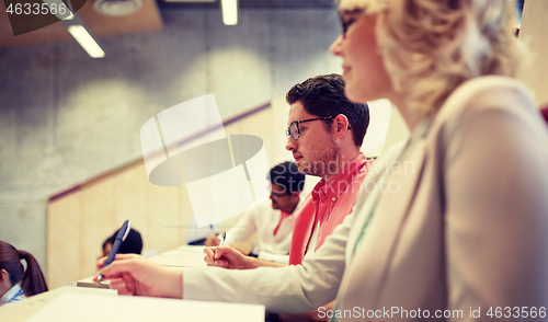 Image of group of students with notebooks in lecture hall