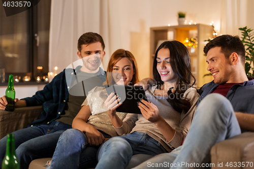 Image of friends with tablet computer drinking beer at home