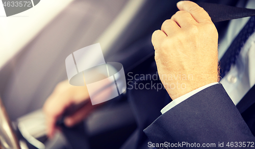 Image of senior businessman fastening car seat belt