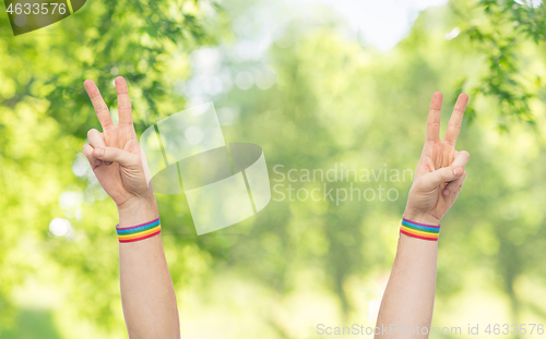 Image of hands with gay pride rainbow wristbands make peace