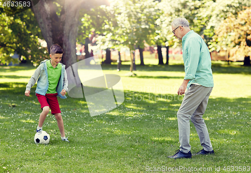 Image of old man and boy playing football at summer park