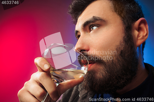 Image of The surprised young man posing with glass of wine.
