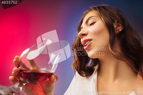 Image of The surprised young woman in party clothes posing with glass of wine.