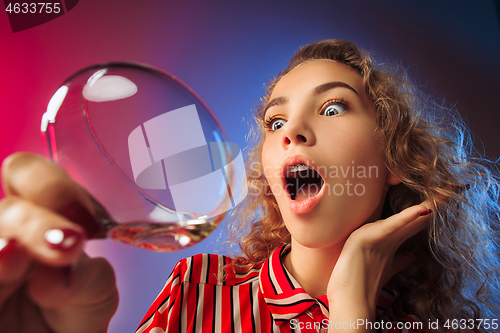 Image of The surprised young woman in party clothes posing with glass of wine.