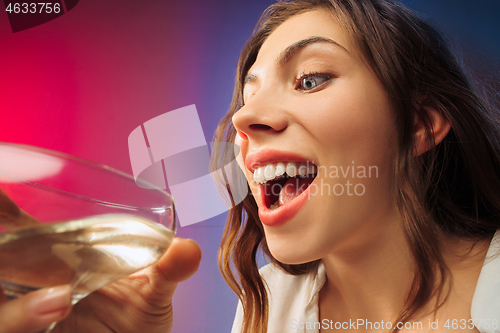 Image of The surprised young woman in party clothes posing with glass of wine.