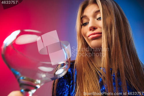 Image of The sad young woman in party clothes posing with glass of wine.