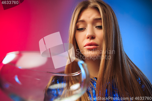 Image of The sad young woman in party clothes posing with glass of wine.