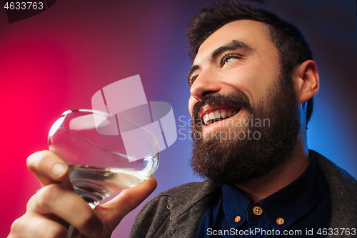 Image of The surprised young man posing with glass of wine.