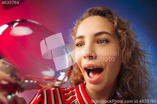 Image of The surprised young woman in party clothes posing with glass of wine.