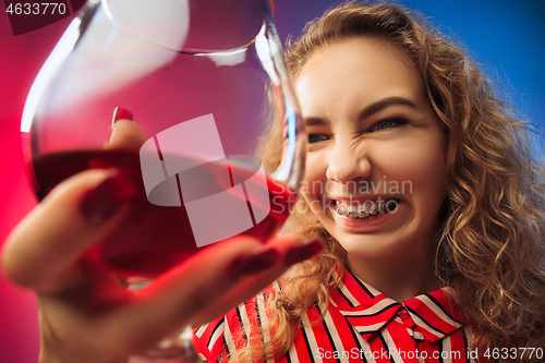 Image of The sad young woman in party clothes posing with glass of wine.