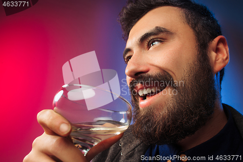 Image of The surprised young man posing with glass of wine.