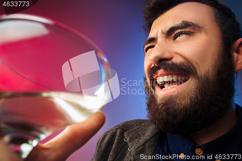 Image of The surprised young man posing with glass of wine.