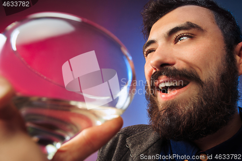 Image of The surprised young man posing with glass of wine.