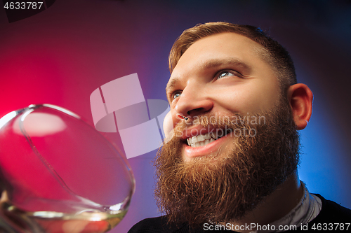 Image of The surprised young man posing with glass of wine.