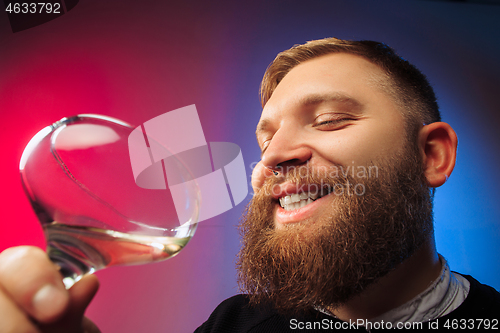 Image of The surprised young man posing with glass of wine.