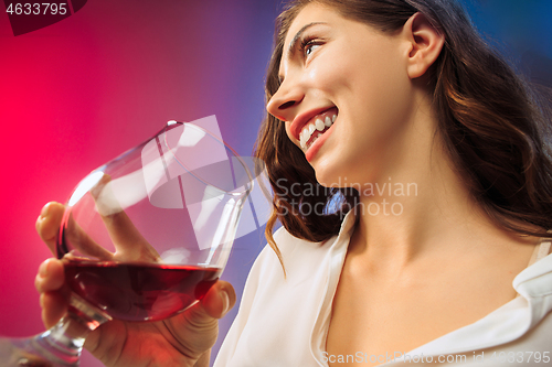 Image of The surprised young woman in party clothes posing with glass of wine.