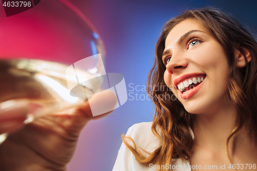 Image of The surprised young woman in party clothes posing with glass of wine.