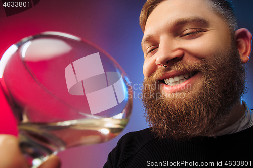 Image of The surprised young man posing with glass of wine.