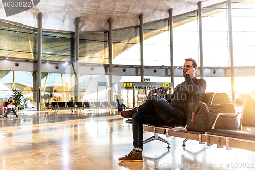 Image of Casual young male using her cell phone while waiting to board a plane at airport departure gates.