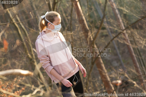 Image of Corona virus, or Covid-19, is spreading all over the world. Portrait of caucasian sporty woman wearing a medical protection face mask while walking in the forest. Corona virus.