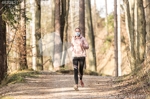 Image of Corona virus, or Covid-19, is spreading all over the world. Portrait of caucasian sporty woman wearing a medical protection face mask while running in nature.