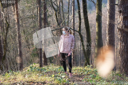 Image of Corona virus, or Covid-19, is spreading all over the world. Portrait of caucasian sporty woman wearing a medical protection face mask while walking in the forest. Corona virus.