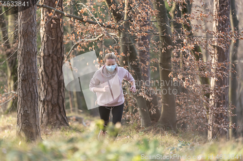 Image of Corona virus, or Covid-19, is spreading all over the world. Portrait of caucasian sporty woman wearing a medical protection face mask while running in nature.