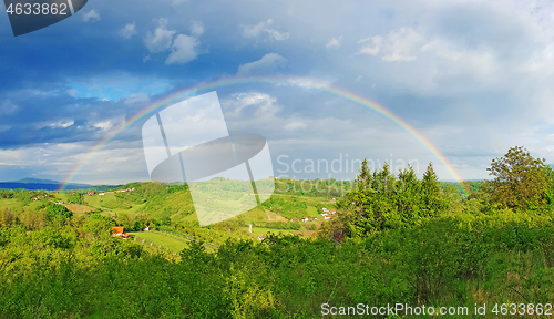Image of Spring rural rainbow landscape, view of green meadows and hills